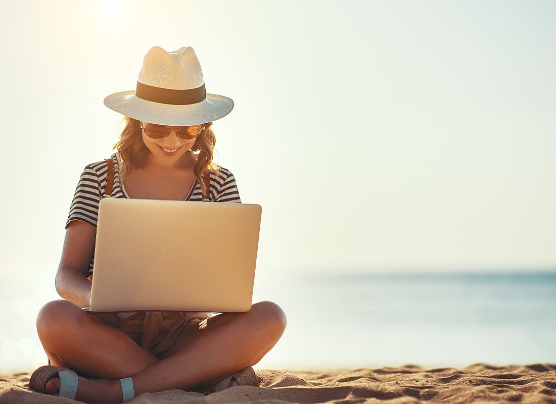 Blog - Young Woman Working With Her Laptop While Sitting on a Beach