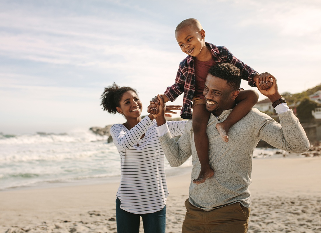 Personal Insurance - Parents Carrying Son on Their Shoulders While Relaxing on the Beach on Vacation